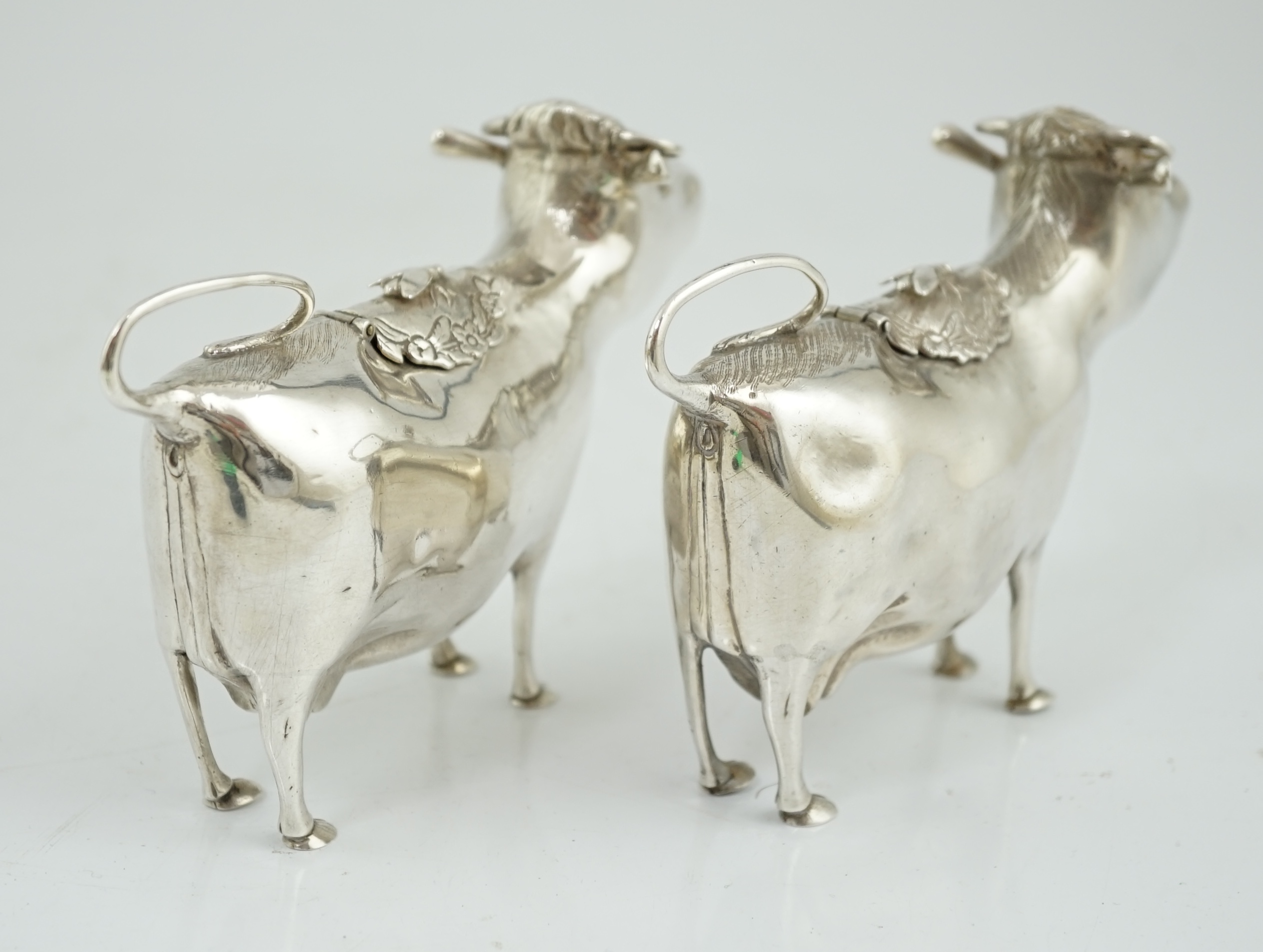 A pair of Elizabeth II silver cow creamers, by Heming & Co